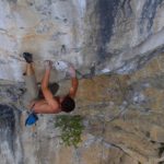 un climber fa una presa di tallone in falesia