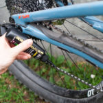 una persona mette l'olio sulla catena di una mtb