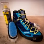 Uno scarpone da trekking con una spazzola e uno spray impregnante