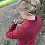 Una donna regola lo smartwatch Suunto 7 in un sentiero