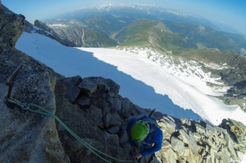 Un alpinista si assicura su un chiodo fisso