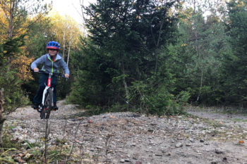 Un bambino in mtb salta un dosso in un sentiero